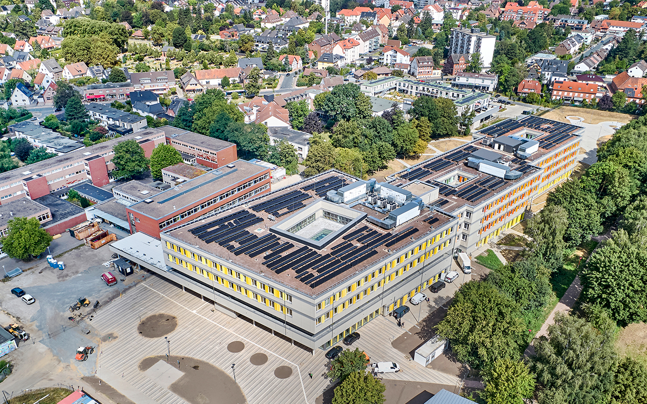 Drohnenaufnahme des Schulcampus Süd in Lehrte nach Fertigstellung des ersten Bauabschnitts. Zu sehen sind die miteinander verbundenen Schulgebäude, weitläufige Außenanlagen sowie die großflächigen Photovoltaikanlagen auf den Dächern des neuen Bildungscampus.