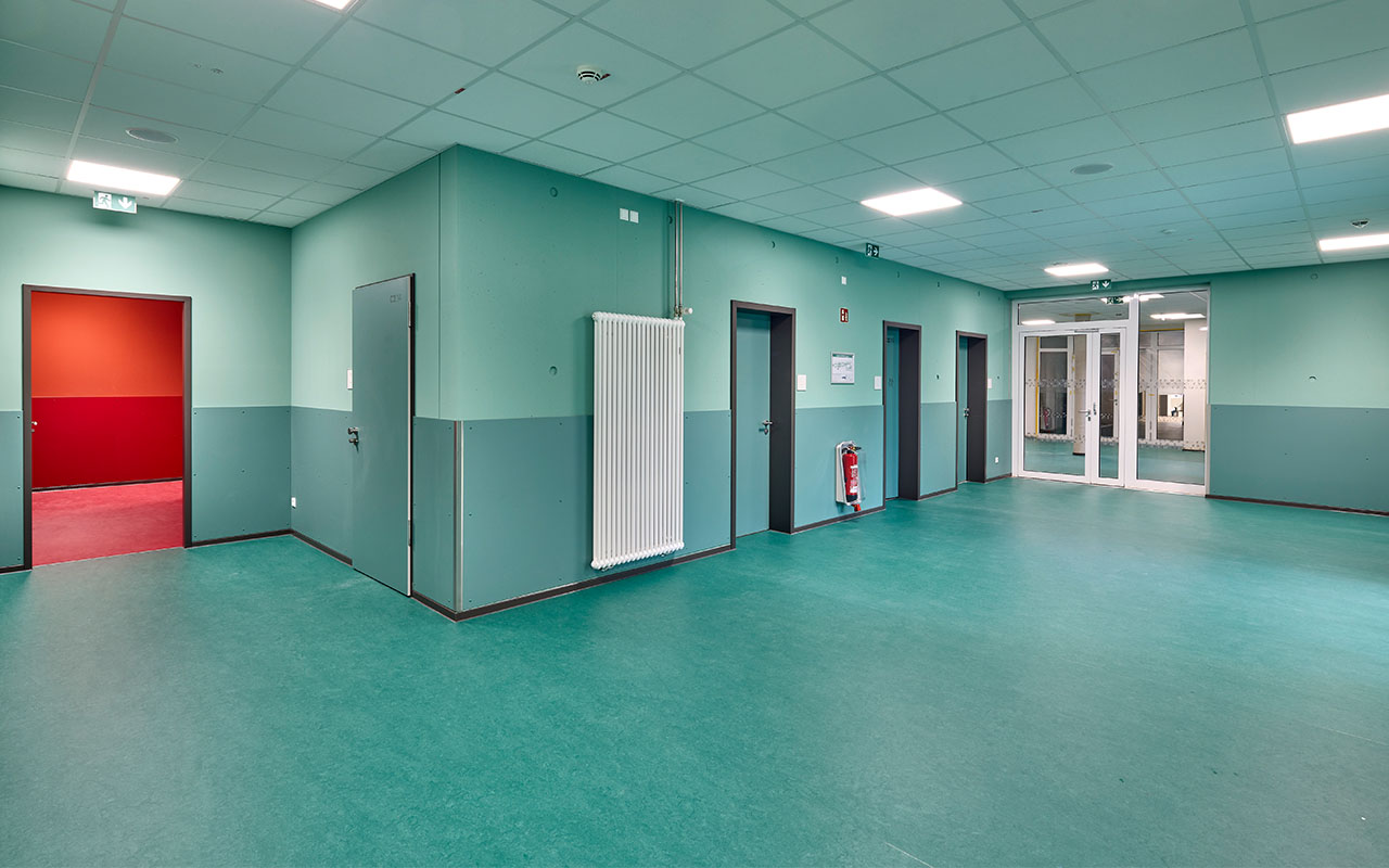Grün gestalteter Innenbereich des Schulcampus Süd, dessen Farbkonzept den Gebäudeteil der Realschule kennzeichnet und die Orientierung innerhalb des Schulgebäudes unterstützt.