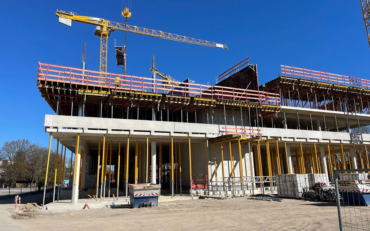 Baufortschritt auf der Baustelle des Schulcampus Süd: Die Deckenschalung über dem zweiten Obergeschoss ist fertiggestellt, während Kräne und Traggerüste für die weiteren Rohbauarbeiten im Einsatz sind.